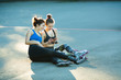 © Alexandr - two young girls in sports suits rest and talk after roller-skating in the courtyard in the street in the summer