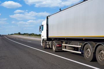 Wall Mural - Truck on road with container and cloudy sky, cargo transportation concept