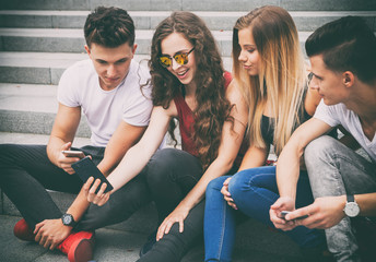 Group of friends sitting together using phone and laughing