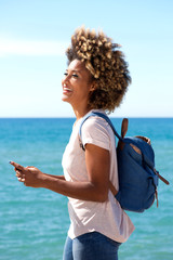 Wall Mural - young black female tourist along the beach with smart phone
