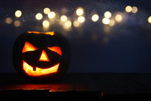 Halloween Pumpkin On Wooden Table In Front Of Spooky Dark Background. Jack O Lantern