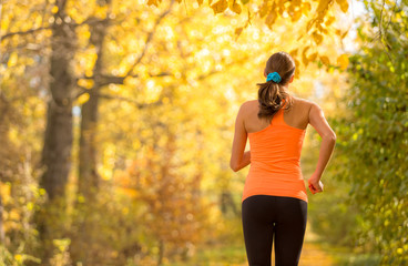 Wall Mural - Young brunette woman running in autumn forest