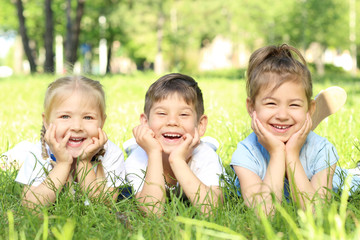 Wall Mural - Cute little children lying on green grass in park