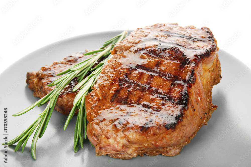 Plate with tasty steaks on white background
