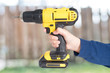 © DD Images - Hand from young kid handling a yellow power drill against wooden background