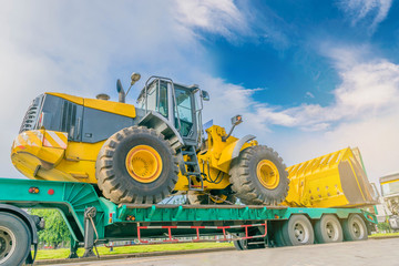 The abstract soft focus of the big tractor on the tow truck with the beautiful sky and cloud, by the beam, light, and lens flare effect tone.