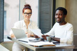 © pressmaster - Multi-ethnic team of financial managers posing for photography while sitting at boardroom table and analyzing statistic data, group portrait