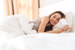 © Drobot Dean - Happy pretty lady lies in bed indoors. Looking camera.