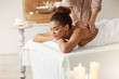 © Cookie Studio - Tender african girl smiling enjoying massage with closed eyes in spa resort.