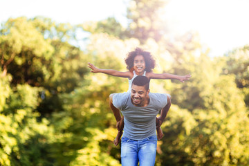 Portrait of young father carrying his daughter on his back