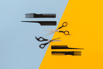 Hairdresser tools on blue and yellow background with copy space, top view, flat lay.