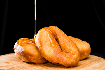 Wall Mural - close-up of sweet fresh delicious donuts throwing with chocolate on round wooden board, dark background