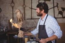 Craftsman Looking At Bird Sculpture In Workshop