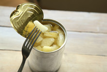 Opened Tin Can Of Canned Pineapple Pieces. Canned Pineapple In Can With Fork On Wooden Table.
