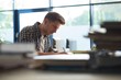 © Wavebreak Media - Side view of young male student studying at desk in classroom
