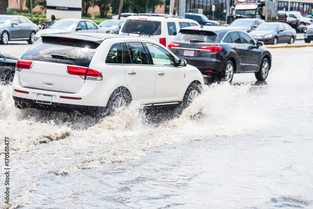Splash by car as it goes through flood water after heavy rains of ...