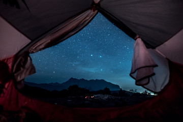 romantic starry sky night view from inside of tent. camp with spectacular starry sky wtih mountain b