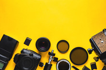 Digital camera, lenses and equipment of the photographer on a yellow background