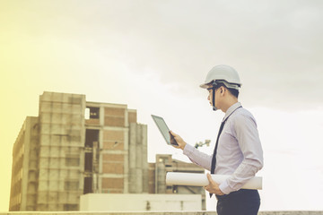 smiling young architect or engineering builder in hard hat with tablet over group of builders at construction site, architect watching some a construction, business, building, industry, people concept