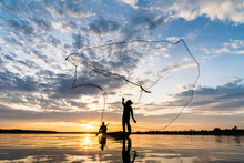 Silhouette Of Fishermen Throwing Net Fishing In Sunset Time At Wanon Niwat District Sakon Nakhon Northeast Thailand.