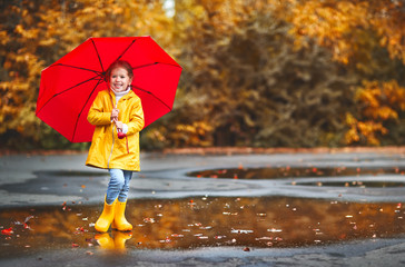 Wall Mural - happy child girl with an umbrella and rubber boots on autumn walk.