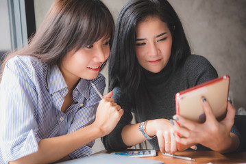 two young Asian woman using tablet at restaurant  