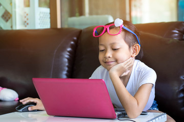 Cute child playing computer at home .