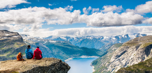 Wall Mural - Couple sitting against amazing nature view on the way to Trolltunga. Location: Scandinavian Mountains, Norway, Stavanger. Artistic picture. Beauty world. The feeling of complete freedom