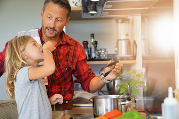 Daddy with daughter cooking together in home kitchen