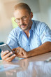 © goodluz - Mature man with eyeglasses typing message on smartphone