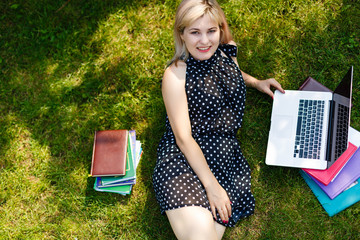 Wall Mural - Young woman with laptop on green grass at park