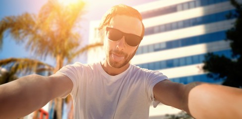 Wall Mural - Composite image of young man taking a selfie