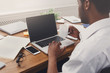 © Prostock-studio - African-american businessman in office type on laptop