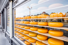 Dutch Cheese Heads On The Shelves Of The Showcase With Reflection Of Delft City In Netherlands