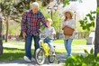 Cute little boy riding on bicycle and his grandparents in spring park