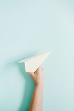 Women Hand Holding White Paper Plane On Pale Blue Background. Flat Lay, Top View.