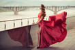 © yuriyzhuravov - Beautiful woman in red fluttering dress. Urban background.