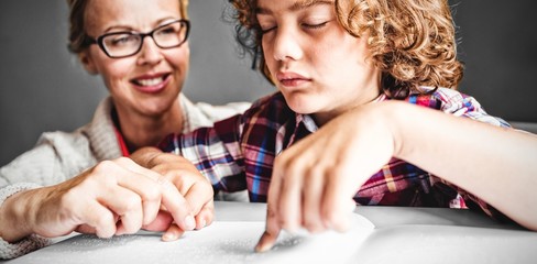 Teacher with boy using braille to read