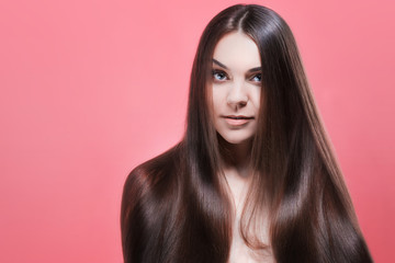 Beauty portrait of brunette with perfect hair, on a pink background. Hair care