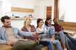 © Monkey Business - Group Of Friends Sitting On Sofa Watching Television Together