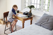 © Monkey Business - Boy Sits At Desk In Bedroom With Digital Tablet Doing Homework
