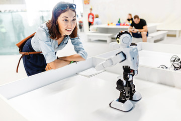 Young adult woman looking at the toy robot at the exhibition