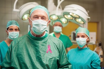 Wall Mural - Composite image of smiling surgeon posing with a team