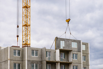 Construction site. Construction cranes and apartment building under construction against blue sky. Concept of construction industry, mortgage, estate, engineering, business, building and architecture