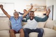 Family cheering while watching television in living room