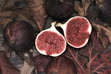 Group Of Fig Fruits On A Wooden Table Surrounded By Dry Leaves