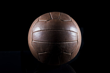 Wall Mural - Old football leather ball on a black background