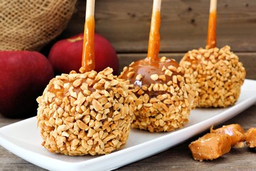 Wall Mural - Sweet caramel apples with nuts on a plate with rustic wood background