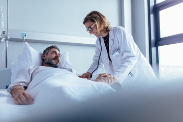 doctor examining patient pulse in hospital room