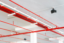 Fire Sprinkler System With Red Pipes Is Placed To Hanging From The Ceiling Inside Of An Unfinished New Building.